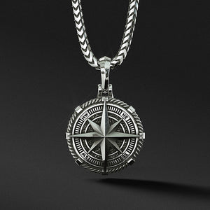 a detailed silver compass pendant hangs from a silver chain