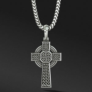 a celtic cross hangs from a silver chain