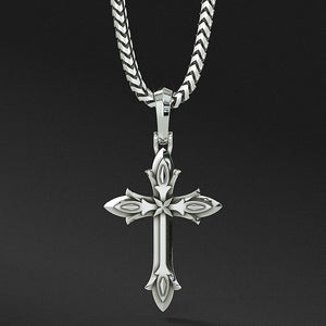 a sterling silver cross necklace with layered decorative sculpting hangs from a chain