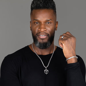 a sterling silver cross necklace is worn by a muscular man with a black shirt