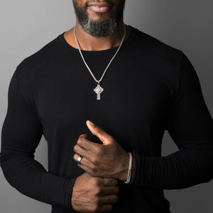 a celtic sterling silver cross necklace is worn by a muscular man with a black shirt