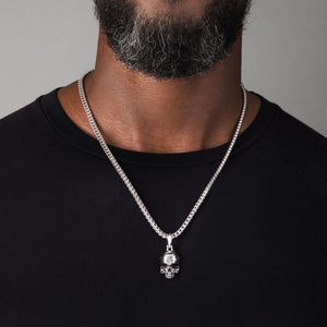 a man in a black shirt wearing a silver necklace and large skull pendant