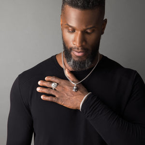 a man wears a polished silver skull pendant and matching skull signet ring