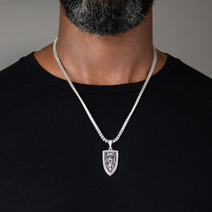 a large silver lion head pendant hangs from a man's franco chain