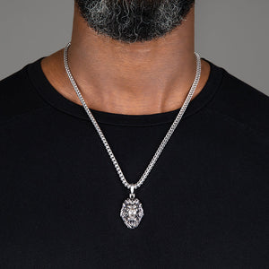 a large silver lion head pendant hangs from a man's franco chain