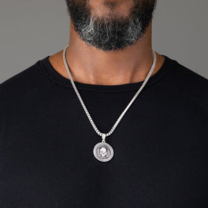 a man in a black shirt wearing a silver necklace and large skull pendant