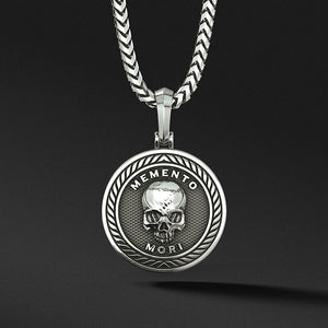 a silver skull pendant in the shape of a medallion with the words memento mori inscribed