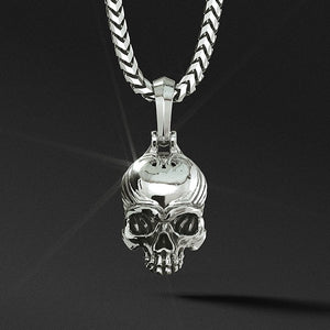 a silver skull pendant hangs on a silver chain