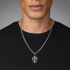 a man in a black shirt wears a shield shaped sterling silver cross pendant