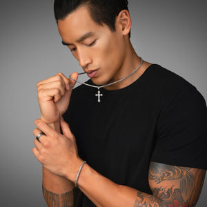 active man pulls on the silvercross necklace he's wearing with a matching silver bracelet
