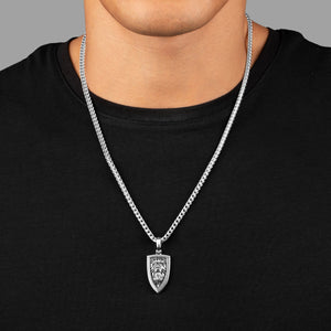 a man in a black shirt wears a sculpted silver lion pendant