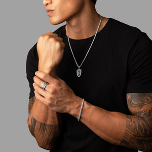 an active man in a black shirt wears a silver crown ring and lion necklace