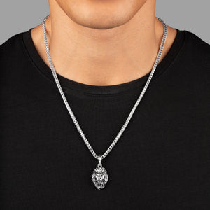 a man in a black shirt wears a polished silver lion head pendant