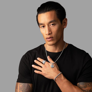 man in a black shirt wearing a silver necklace, skull ring and skull pendant