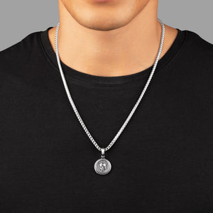 a man in a black shirt wearing a silver necklace and small skull pendant