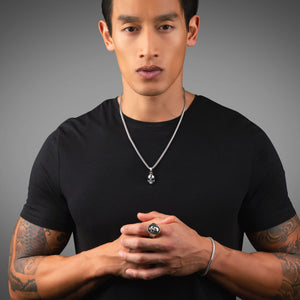 man in a black shirt wearing a silver necklace, skull ring and silver skull pendant