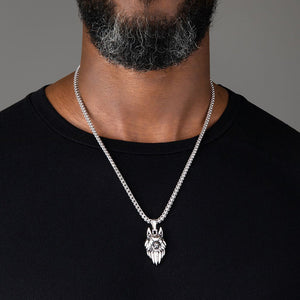 a large sterling silver wolf pendant hangs from a mans necklace