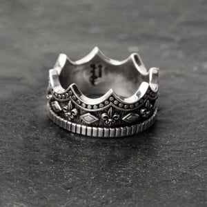 crown-shaped mens silver wedding band lays on a slate surface