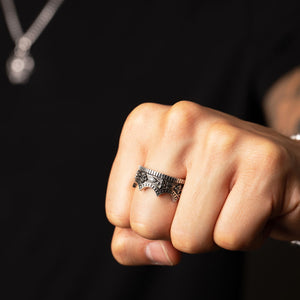a crown ring with scuplted details is displayed on the hand of a man