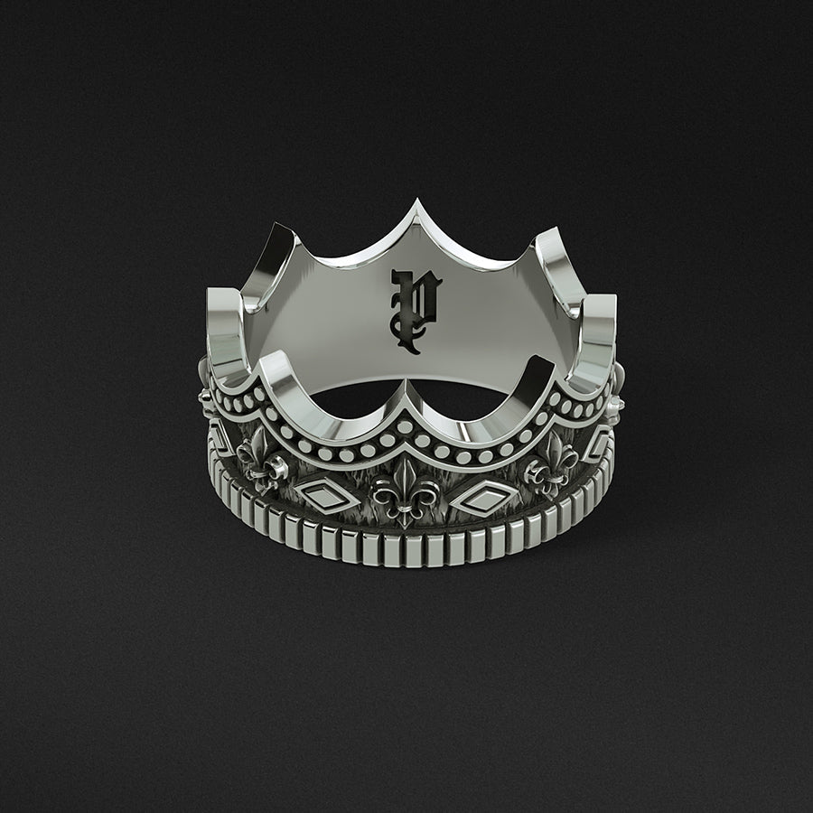 a mens silver ring sculpted into a crown lies on a black surface