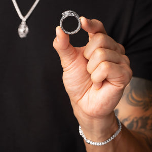 man holds a polished silver dragon ring to display the details