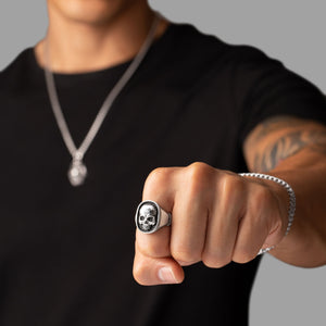 man shows his fist and the skull ring that adorns it