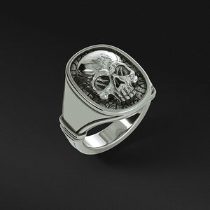a polished skull ring made from sterling silver stands and shines on a black surface