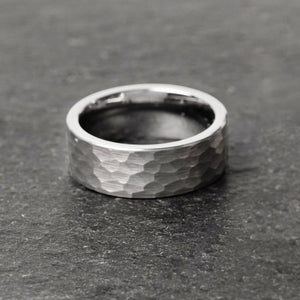 a tungsten ring sits on a black slate surface