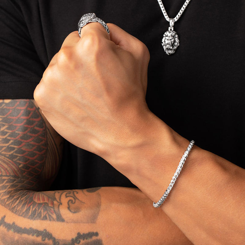 a close view of a mans arm that is showcasing a 4mm silver franco bracelet and dragon ring