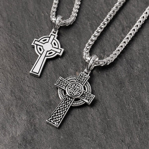 two celtic silver cross chains lie on a slate surface