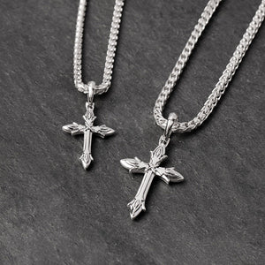 two silver cross chains lie on a slate surface
