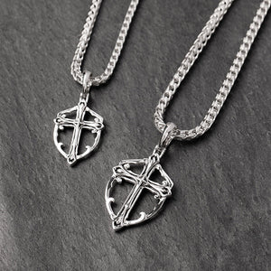 two unique silver cross chains lie on a slate surface