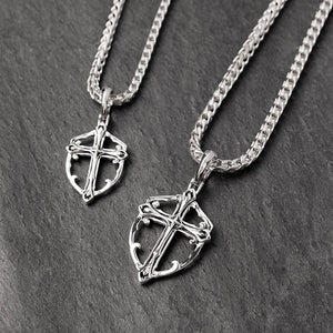 two unique silver cross chains lie on a slate surface
