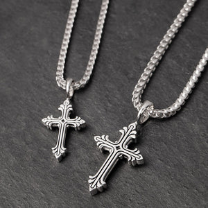 two silver cross chains lie on a slate surface