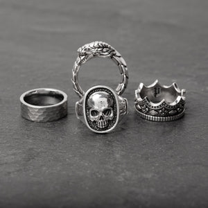 a few skull rings for men made from polished sterling silver shine as they lay on slate